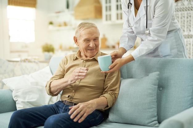 Oudere man die thuis een warm drankje gaat drinken