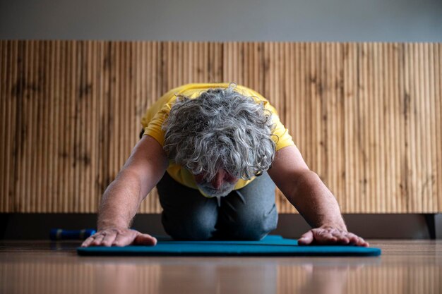 Foto oudere man die yoga of pilates beoefent en een kinderhouding inneemt