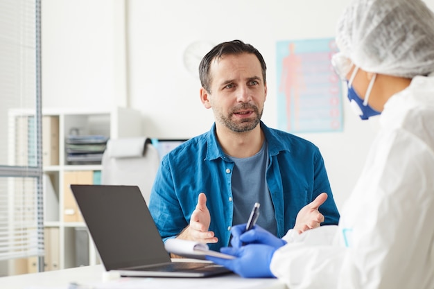 Oudere man die zijn dokter bezoekt, zit hij en vertelt over zijn klachten op kantoor