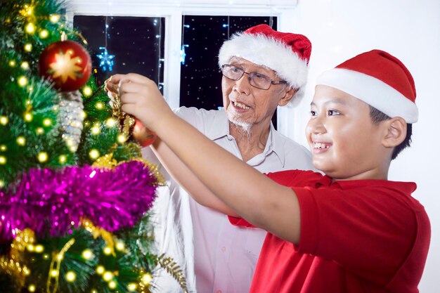 Oudere man en kleindochter met kerstboom