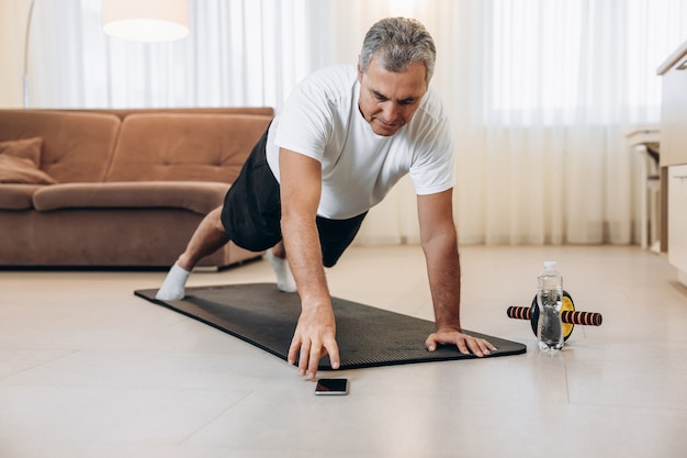 Oudere man grijpt naar telefoon om van muziek te wisselen tijdens het sporten