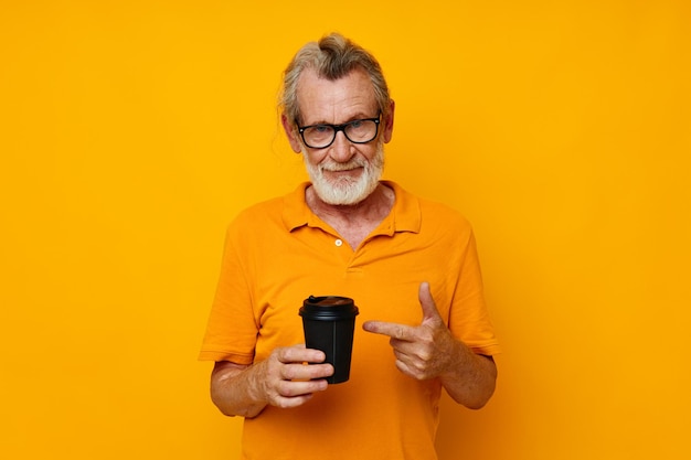 Oudere man in een gele t-shirt een glas met een drankje gele achtergrond