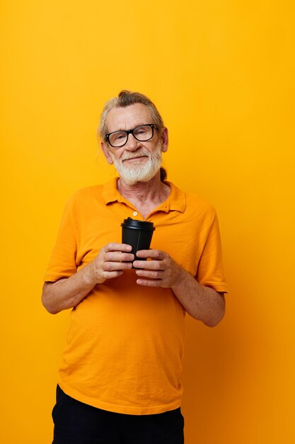 Oudere man in een gele t-shirt een glas met een drankje gele achtergrond