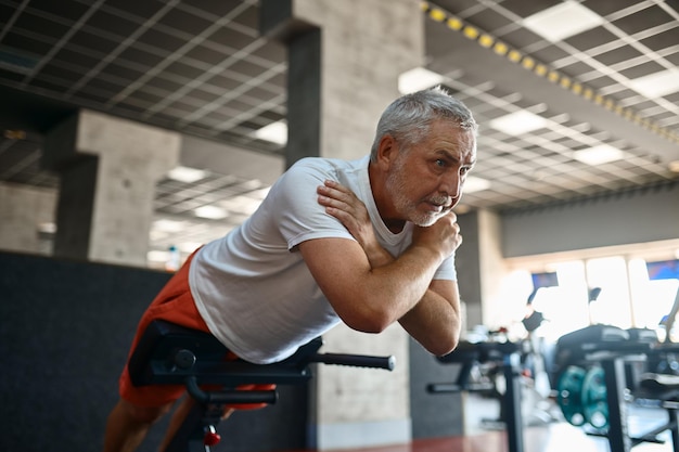 Oudere man in sportkleding die buikspieroefeningen doet, gym