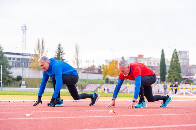 Oudere man in startpose in een lopende atletiekbaan