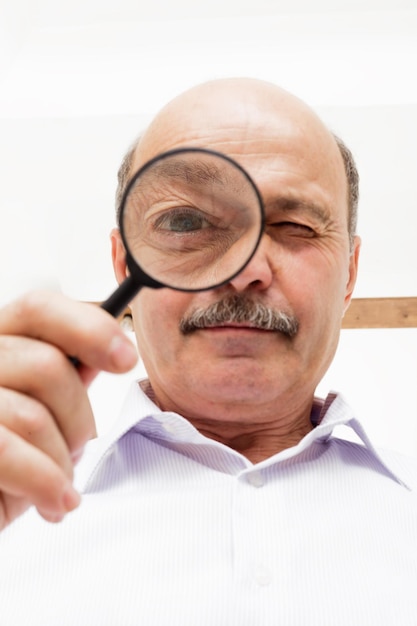 Oudere man kijkt naar iets door een vergrootglas