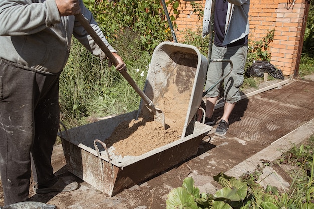 Oudere man kneedt cement voor het gieten van een tuinpad tuinbouwwerkzaamheden