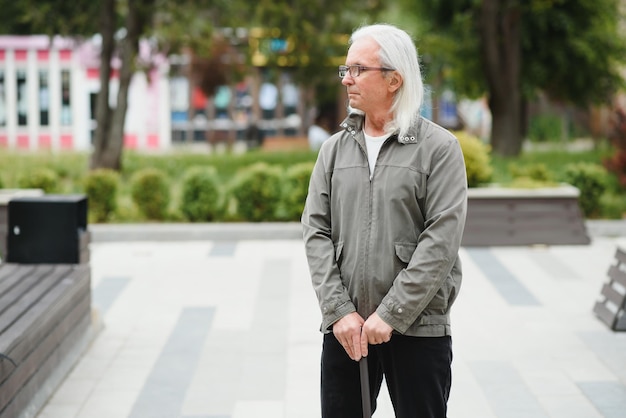 Oudere man loopt met een wandelstok in een lentepark in de stad