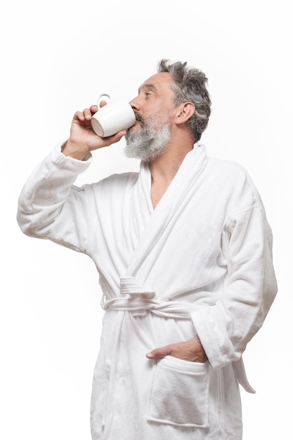 Oudere man met baard in badjas die een kopje koffie drinkt met witte achtergrond