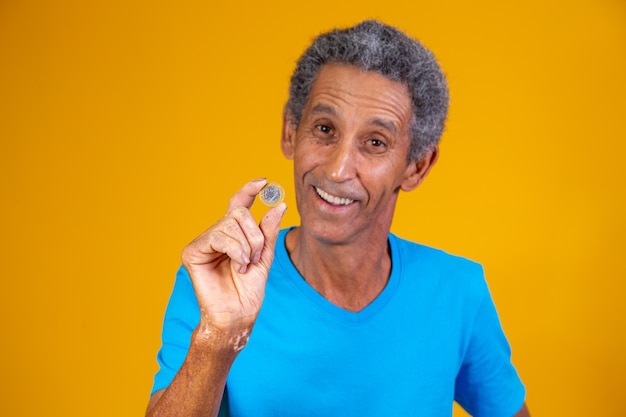 Oudere man met een Braziliaanse echte munt in zijn hand
