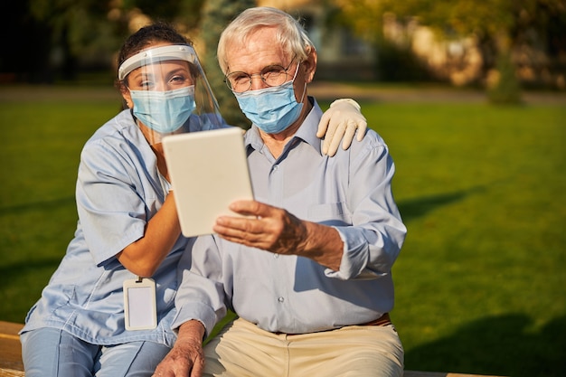 Oudere man met mooie vrouw die naar het scherm van de tablet kijkt