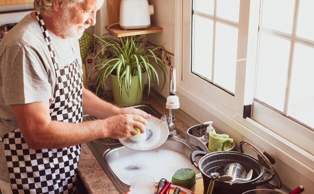 Oudere man reinigt bord in de keuken thuis