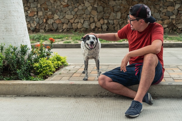 Oudere man zit buiten met zwart-witte hond