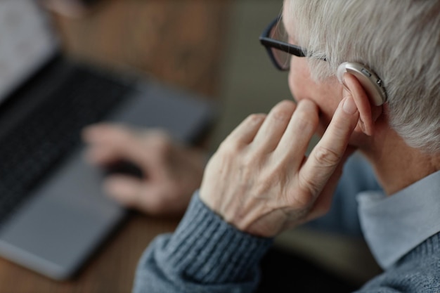 Oudere mannen hand afstemmen gehoorapparaat drukken met de vinger op het apparaat thuis