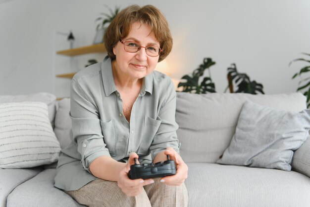 Oudere persoon die plezier heeft met het spelen van een console met een videogame op de bank