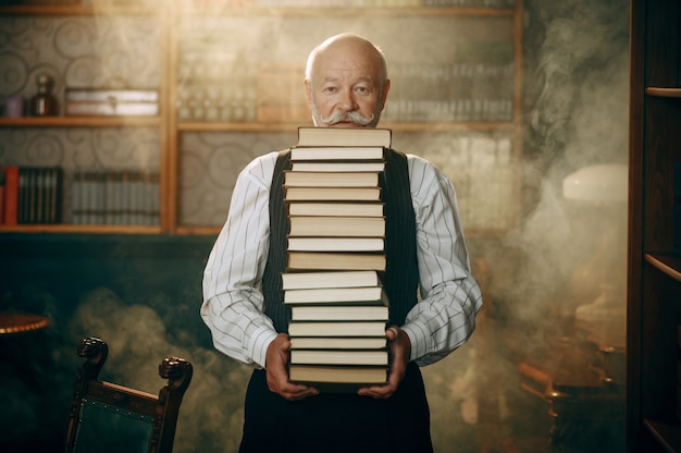 Oudere schrijver houdt stapel boeken in kantoor aan huis