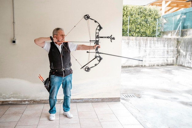 Oudere senior boogschutter boog schieten Volwassen man training het bereiden van boog en pijl voor de sport