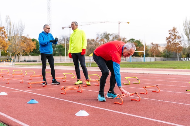 Oudere sportman in rood regelt behendigheidsapparatuur op het spoor terwijl hij bespreekt