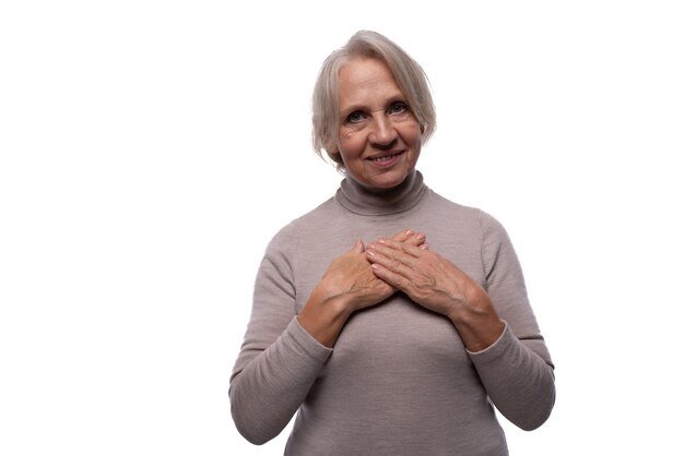 Oudere vriendelijke vrouw met grijs haar op een witte achtergrond