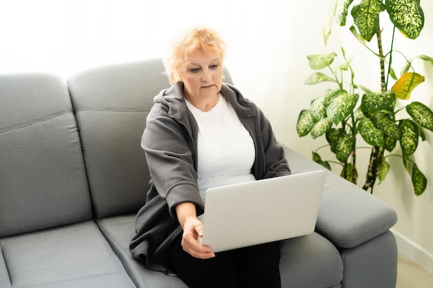 Oudere vrouw die een laptopcomputer thuis met behulp van.