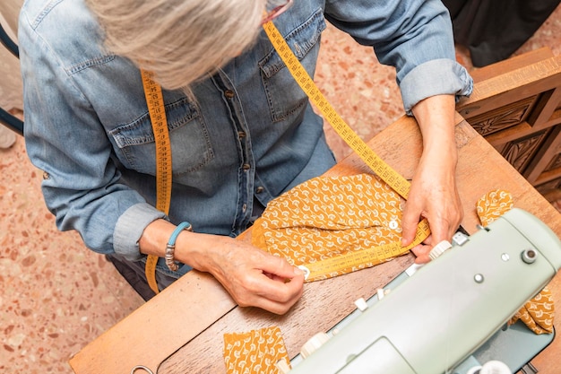 Foto oudere vrouw die een oranje stoffen schroot meet met een meetlint