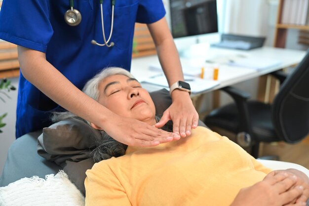Oudere vrouw die een reiki-behandeling ondergaat met een therapeut Concept voor alternatieve geneeskunde en geestelijke gezondheid