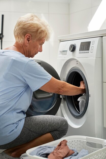 Oudere vrouw die een wasmachine laadt