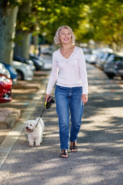 Oudere vrouw die met een hond buiten loopt.