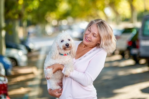 Oudere vrouw die met een hond buiten loopt.