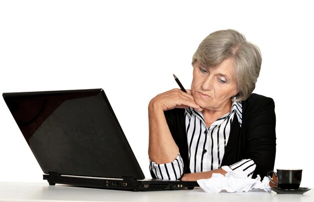 oudere vrouw die met laptop op witte achtergrond werkt