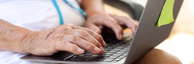 Oudere vrouw die op laptop typt, is op zoek naar informatie over internet, online vrije tijd of werk