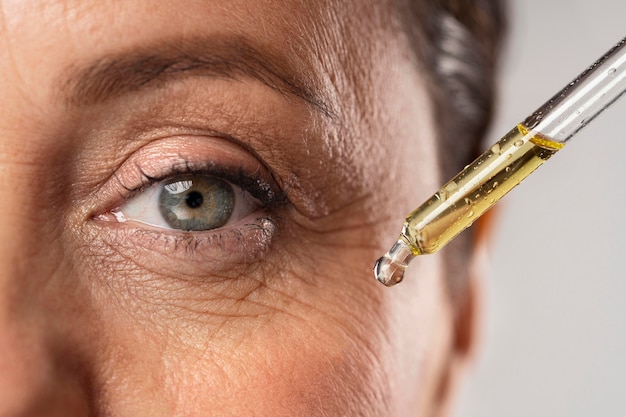 Oudere vrouw die serum gebruikt voor haar oogrimpels