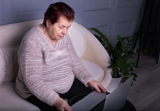 Oudere vrouw die thuis een laptop op tafel gebruikt