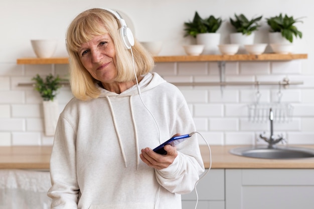 Oudere vrouw die thuis van muziek op hoofdtelefoon geniet