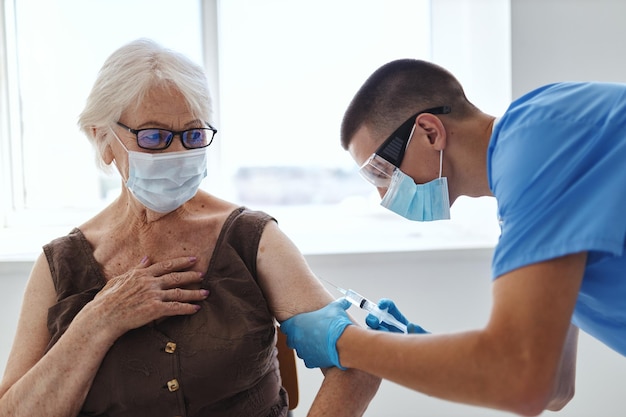 Oudere vrouw en arts in ziekenhuis voor vaccinatie met medisch masker