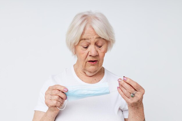 Oudere vrouw in casual t-shirt en medische masker lichte achtergrond