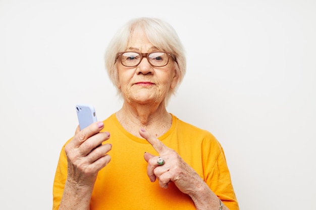 Oudere vrouw in een gele t-shirt poseren communicatie via telefoon close-up emoties