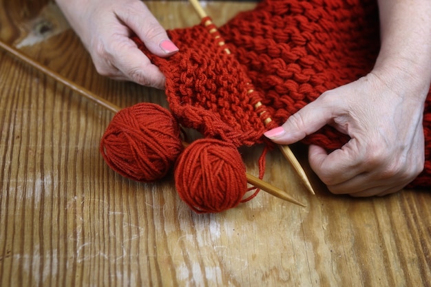 Oudere vrouw is bezig met het breien van warme truien voor haar kleinkinderen