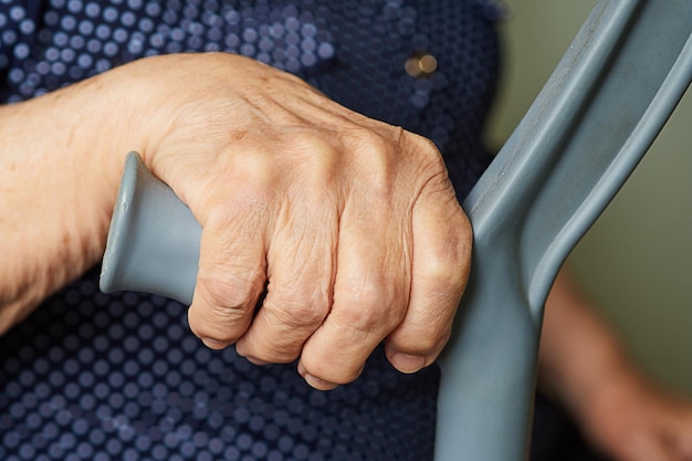 Oudere vrouw leunt op een kruk en probeert op te staan Hand close-up