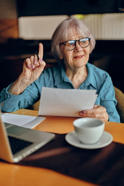 Oudere vrouw met bril zit aan een tafel voor een laptop Sociale netwerken ongewijzigd