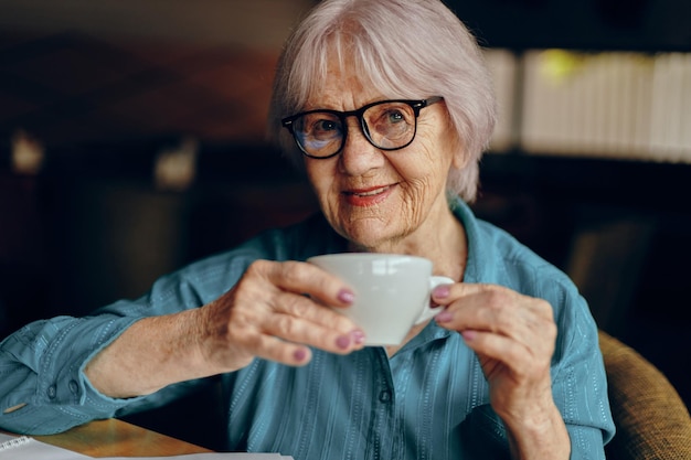 Foto oudere vrouw met bril zit aan een tafel voor een laptop sociale netwerken ongewijzigd