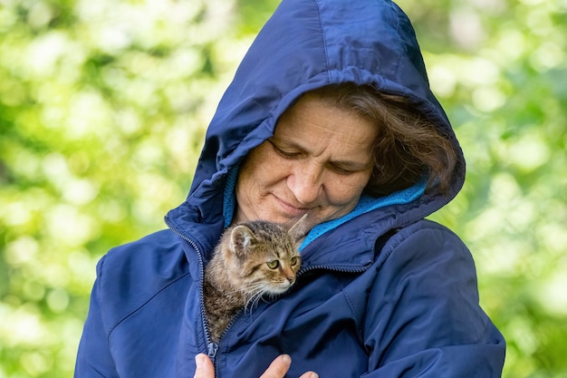 Oudere vrouw met een klein gestreept kitten, een kitten in de armen van een vrouw