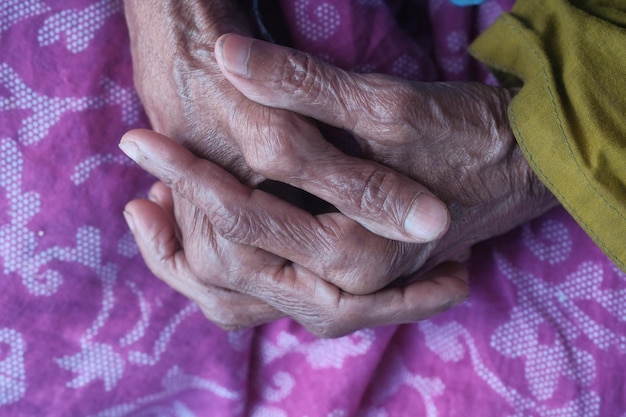 Oudere vrouw met gevouwen handen handen van een oude vrouw dichtbij