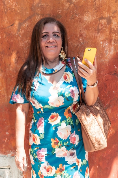 Oudere vrouw met lang haar en haar telefoon op straat.