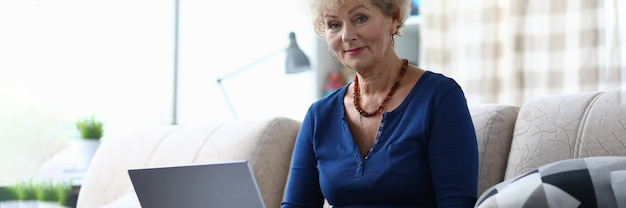 Oudere vrouw met laptop zit op de bank