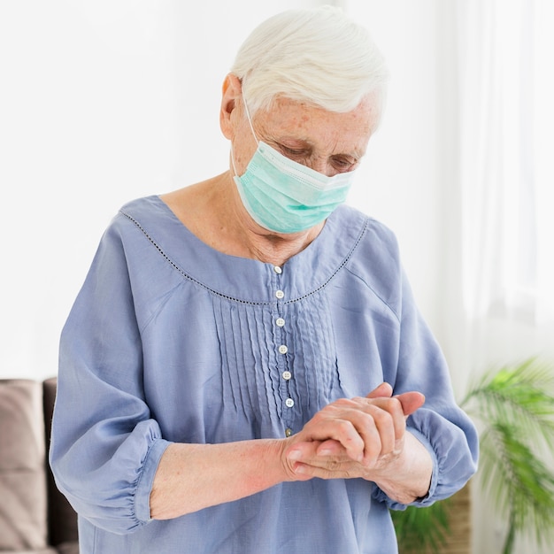 Oudere vrouw met medische masker bidden