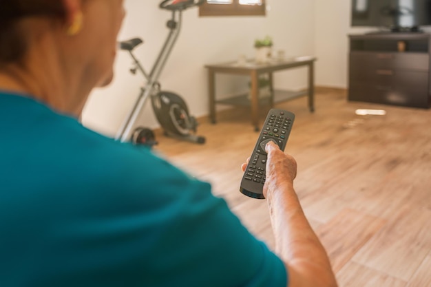 Foto oudere vrouw onherkenbaar met afstandsbediening van tv