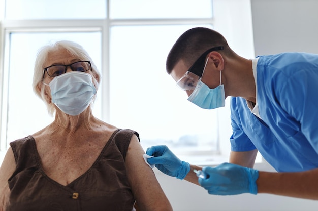 Oudere vrouw patiënt naast dokter vaccinatie pandemisch ziekenhuis