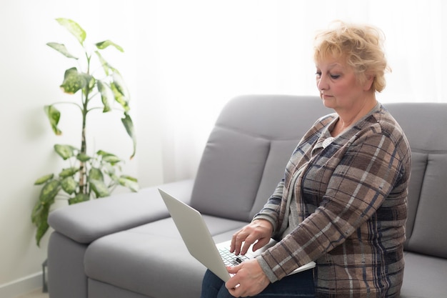 oudere vrouw senior op de computer communiceert laptop, grootmoeder