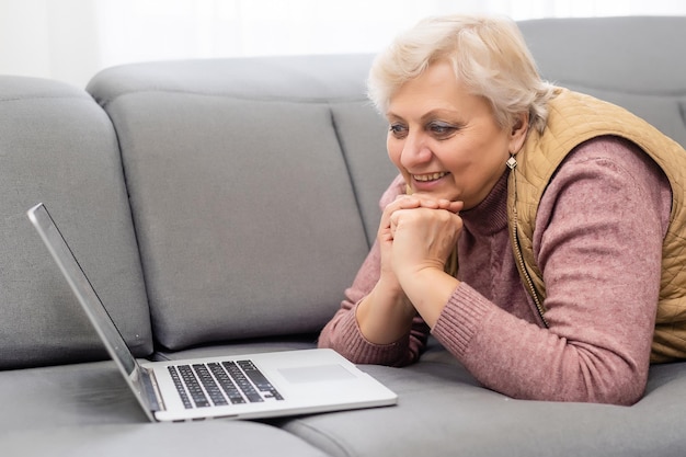 Oudere vrouw videobellen op laptop, zwaaien naar scherm, chatten met kinderen, vrije ruimte.